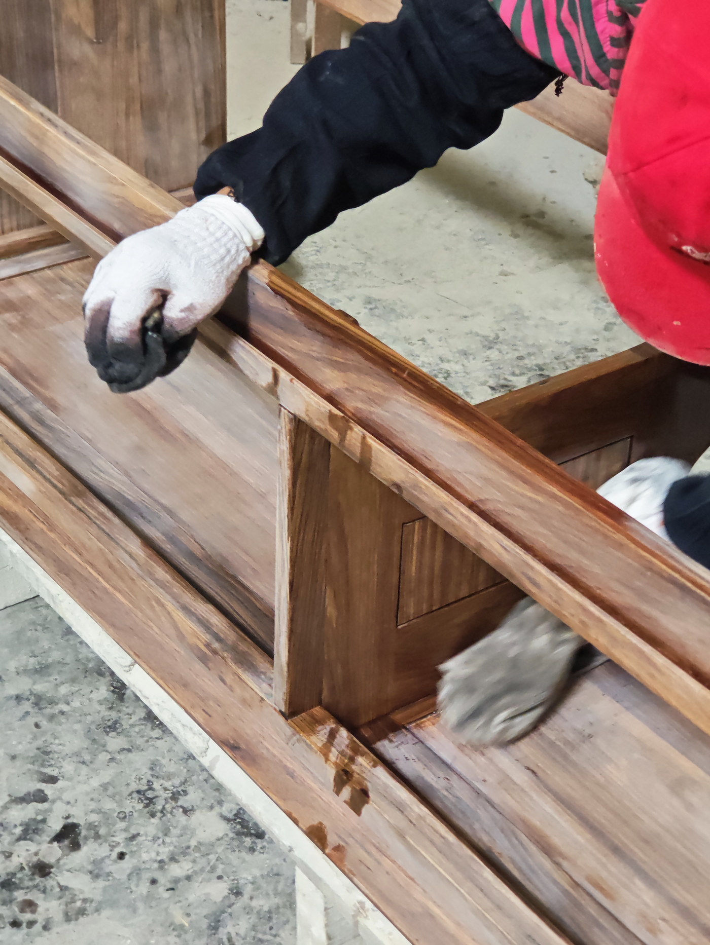 A worker hand-sanding the solid wood frame of a bathroom vanity