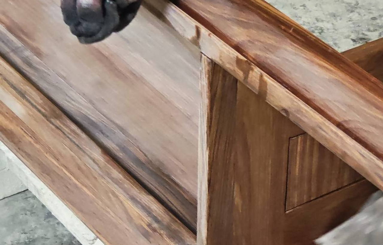 Gloved hands sanding the solid wood frame of a bathroom vanity in the workshop