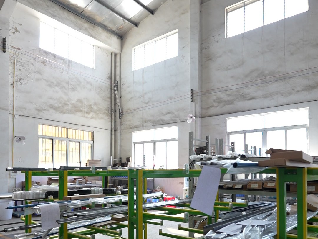 Green and yellow steel assembly racks in a bright shower enclosure production hall