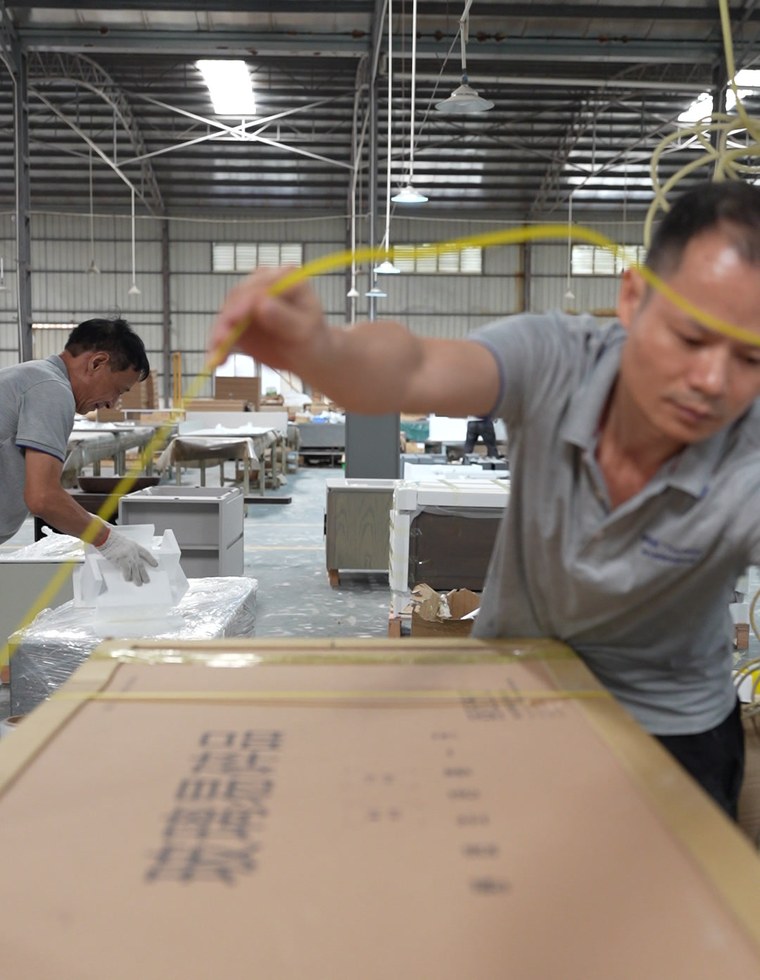 A worker measuring a packed carton with a tape measure in the warehouse