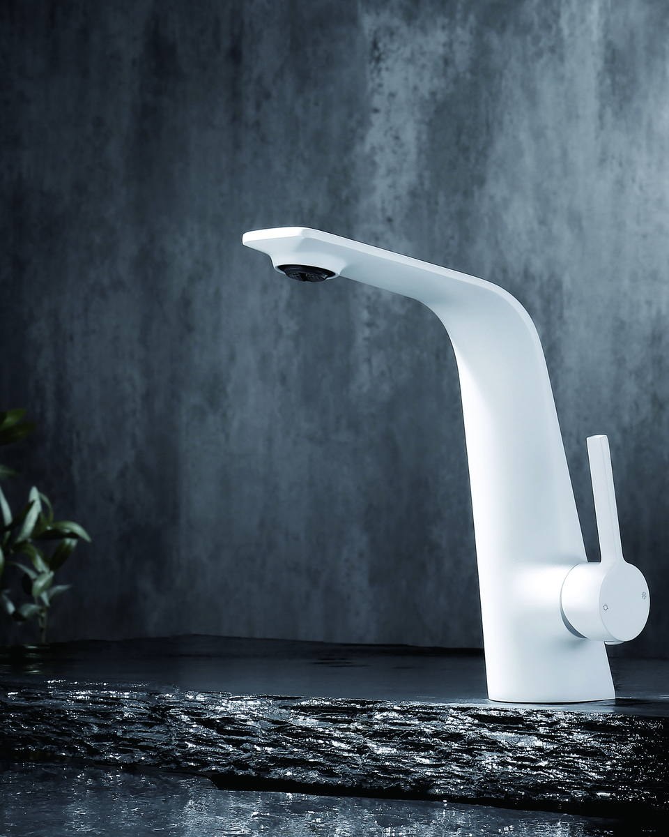 A white basin faucet on a dark stone counter