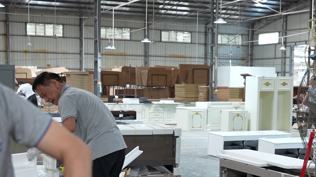 A worker checking a packed carton on a bench in the warehouse