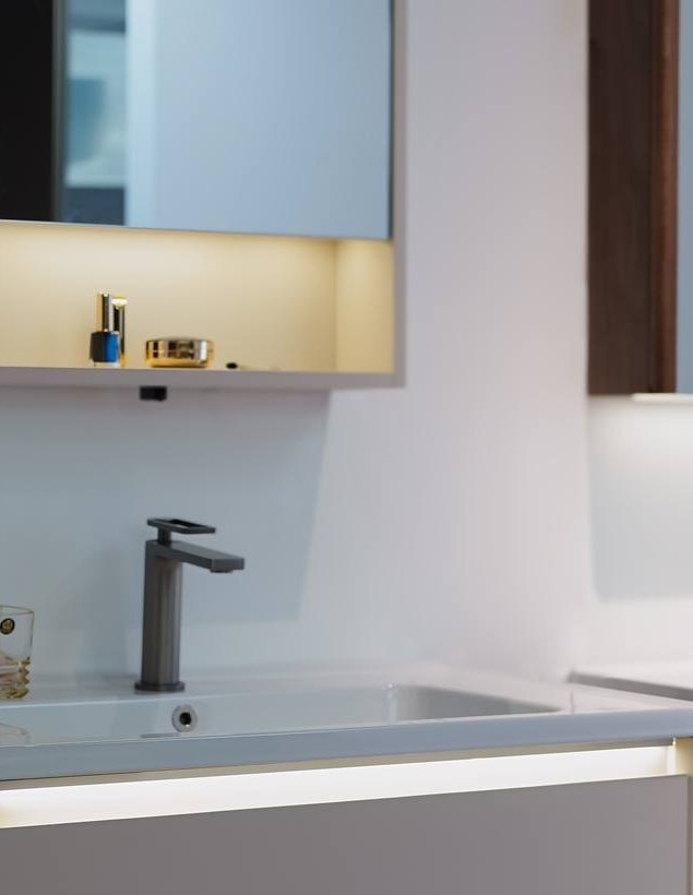 A white wall-mounted vanity with a tall basin tap