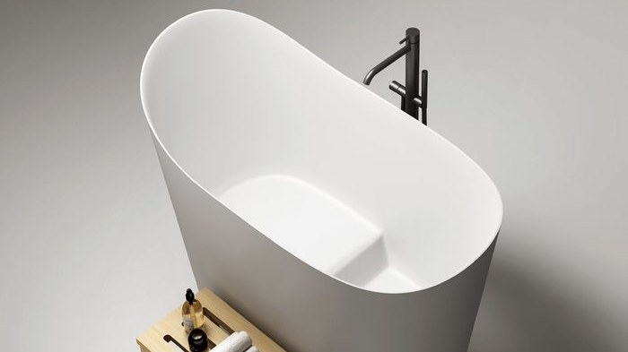 A white soaking tub with a wooden stool beside it