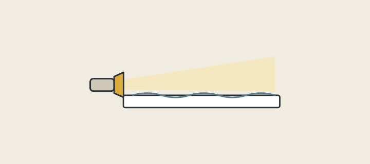 Illustration of a low hand lamp with its beam skimming a slightly wavy surface