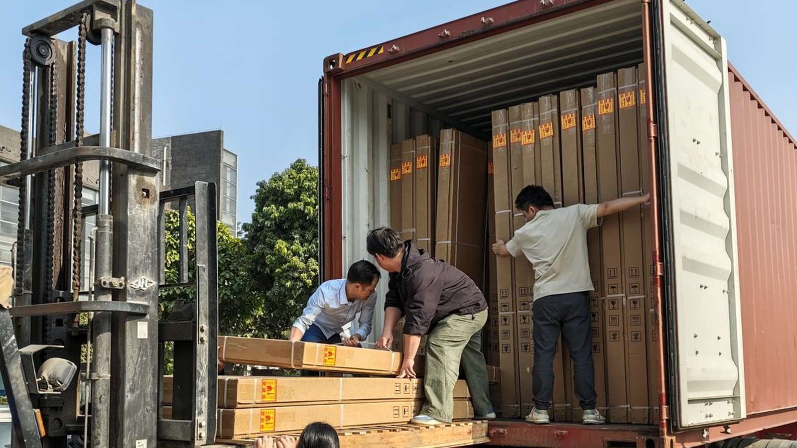 Workers loading long bathtub cartons into a shipping container for export