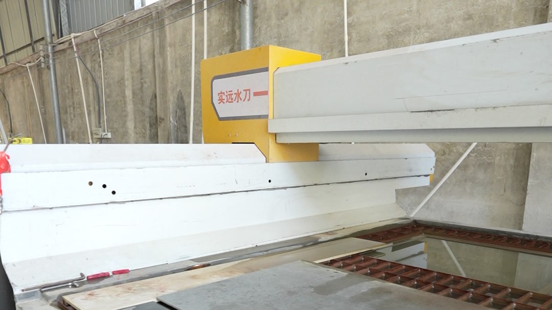A worker feeding a sheet panel into a machine in the workshop