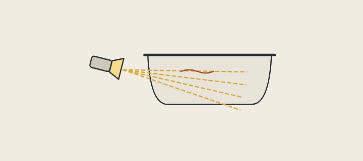 Illustration of a lamp held low beside a tub with rays skimming the tub wall