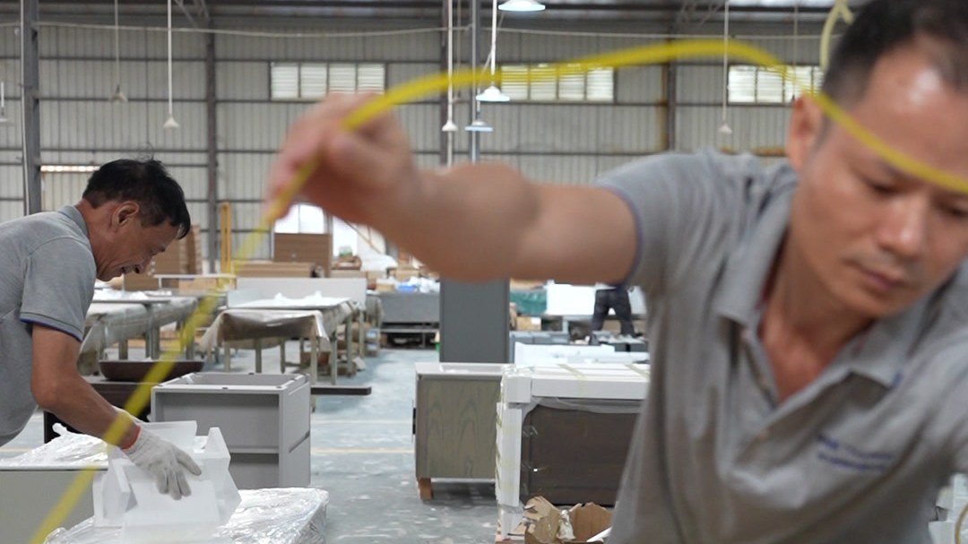 A worker measuring a packed carton with a tape measure in the warehouse