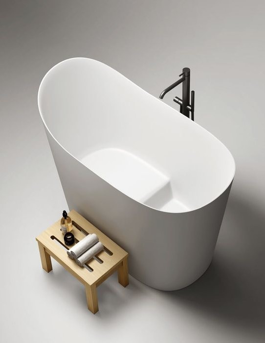 A white soaking tub with a wooden stool beside it