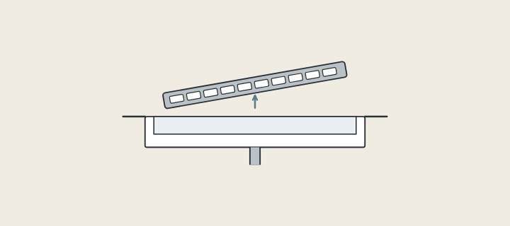 Illustration: a linear drain channel in a floor with its grate lifted out above it