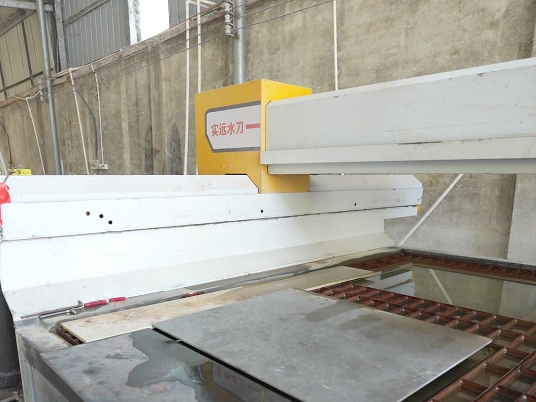 A worker feeding a sheet panel into a machine in the workshop