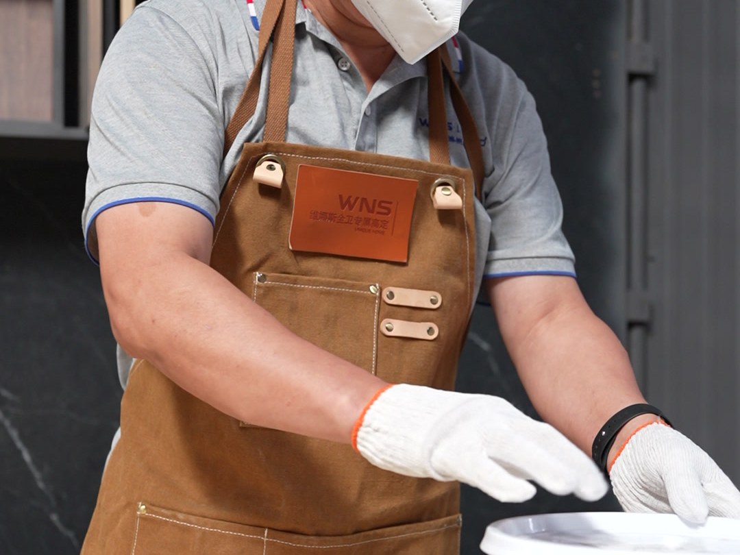 Gloved hands stirring a finish mixture beside a basin