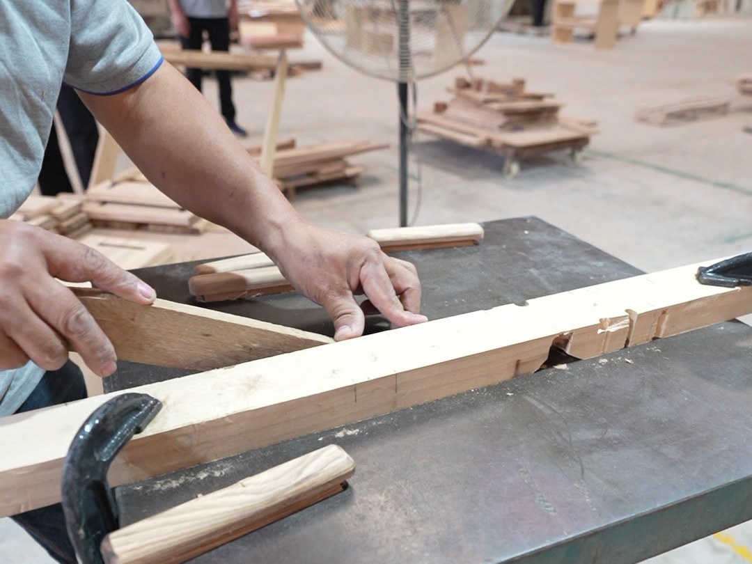 A worker machining a solid wood vanity rail on the workshop floor