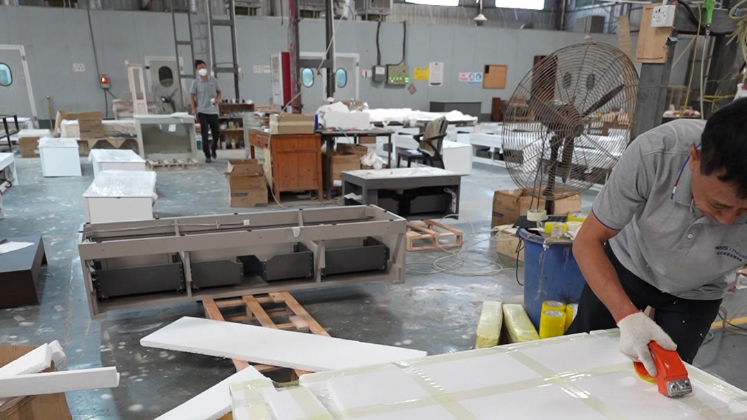A worker wrapping a packed unit on a timber pallet in the workshop