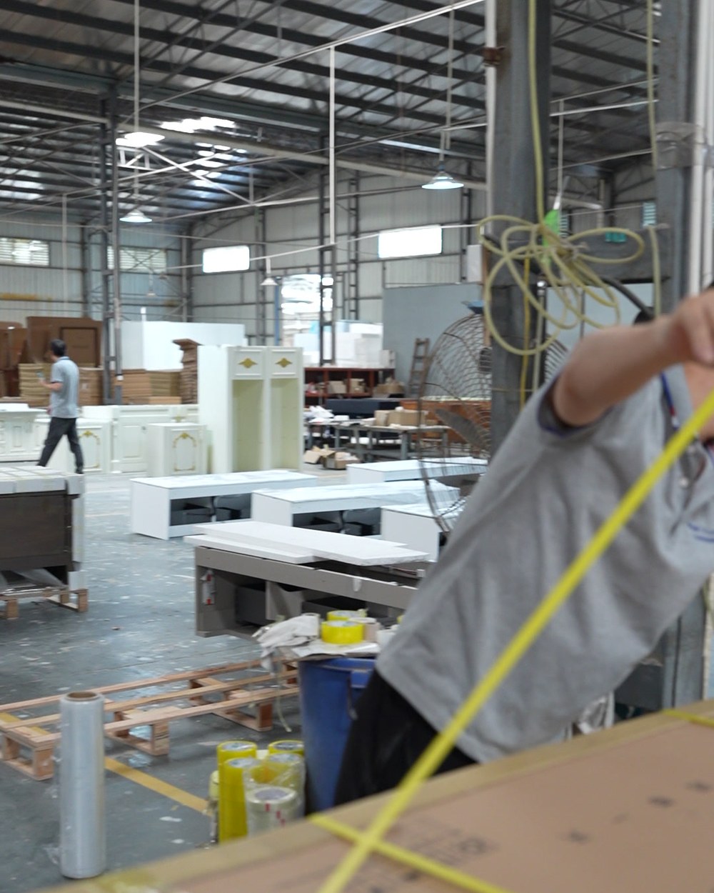 A worker holding a tape measure across a packed carton