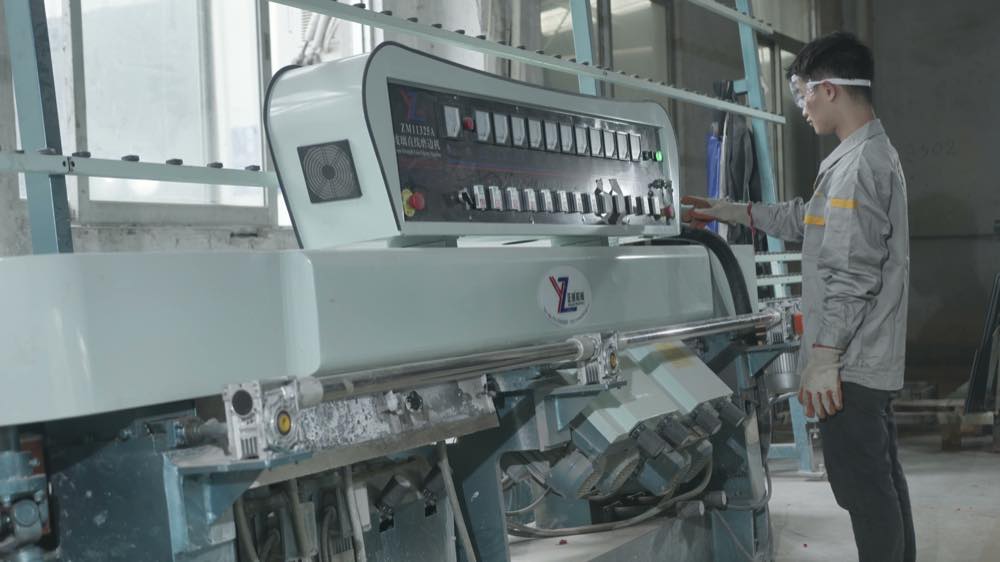 Worker operating a glass edge-finishing machine