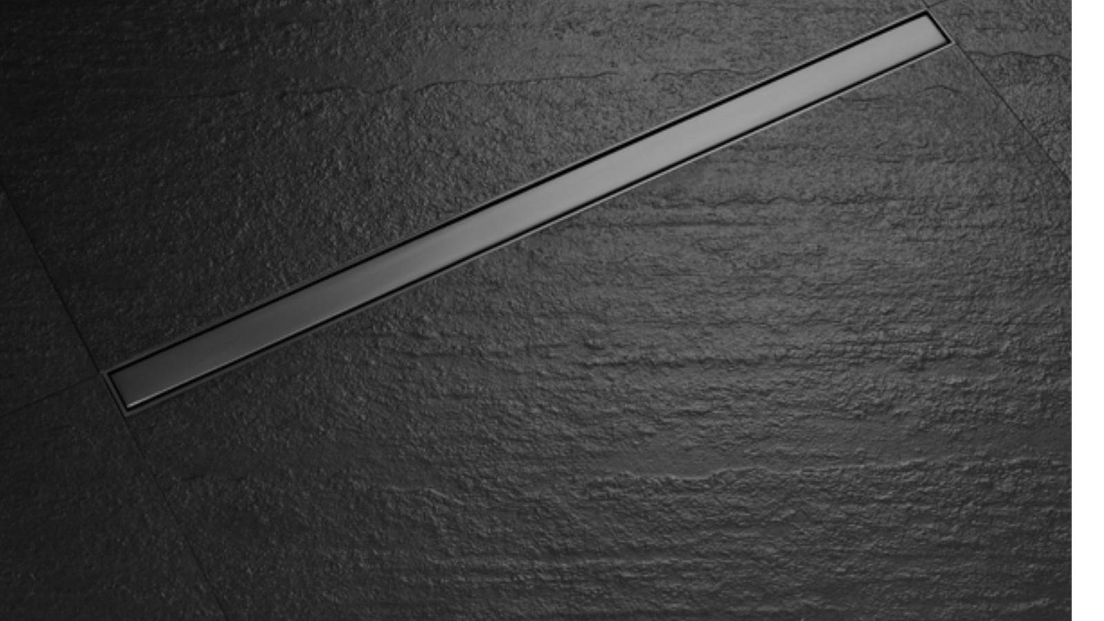 A long linear floor drain in dark stone tiling