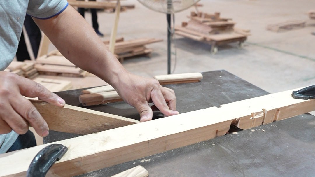 A worker machining a solid wood vanity rail on the workshop floor