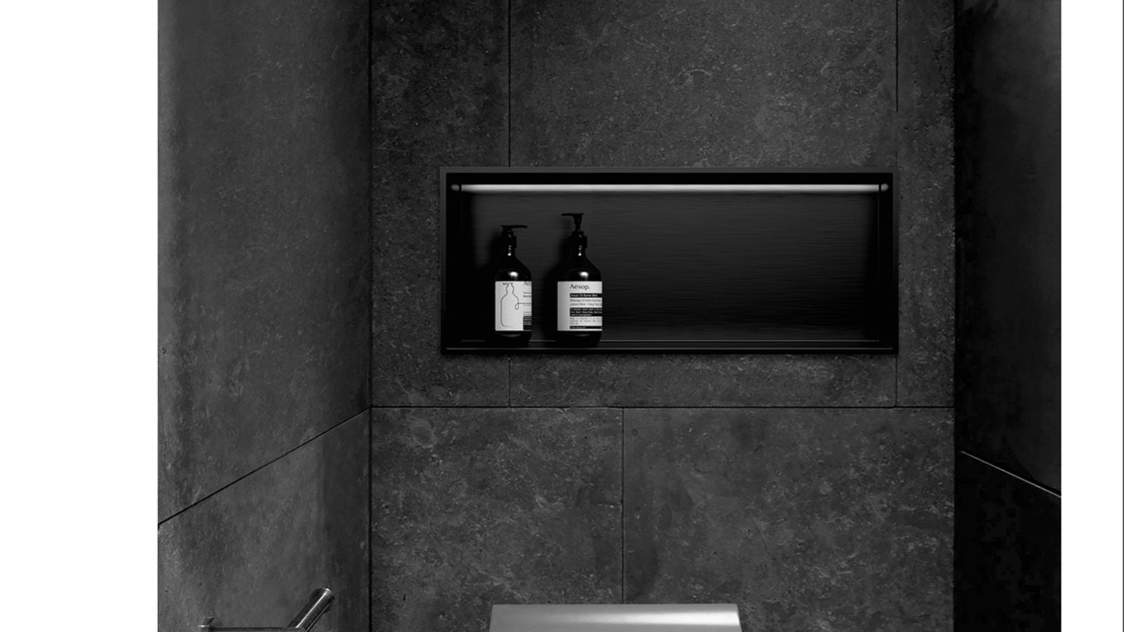 A recessed storage niche in a dark tiled wall