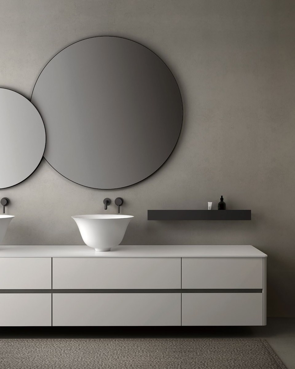 Two round lit mirrors above a double vanity with oval basins