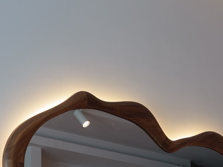 Backlit halo behind the sculpted walnut mirror