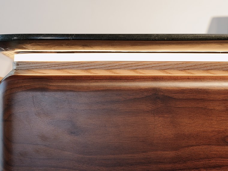 Lit seam between the stone top and the walnut body