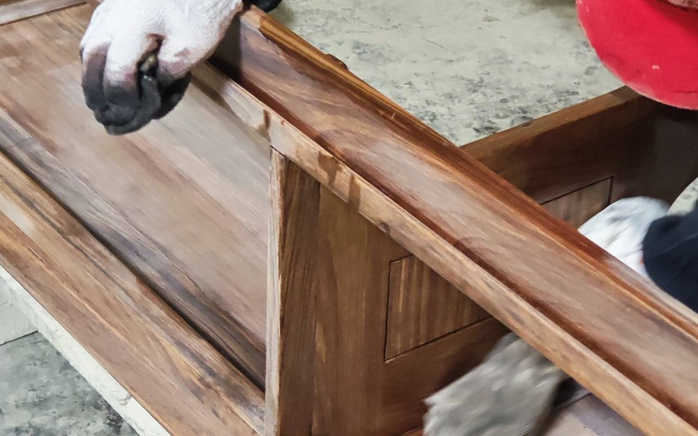 A worker hand-sanding the solid wood frame of a bathroom vanity