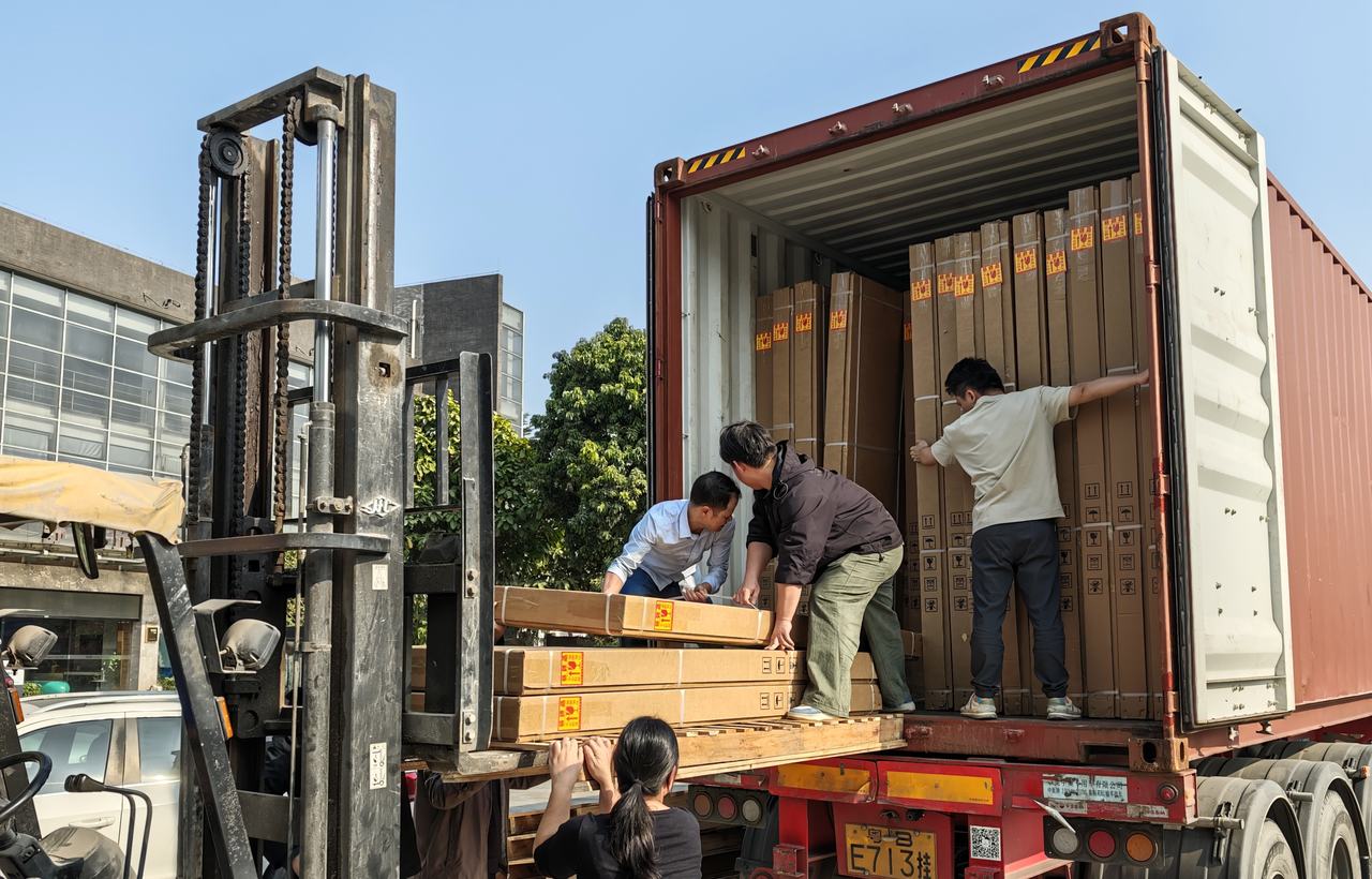 Workers and a forklift loading packed bathroom vanity cartons into a shipping container