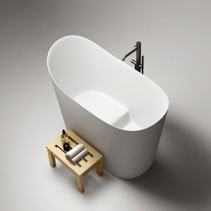 A white soaking tub with a wooden stool beside it