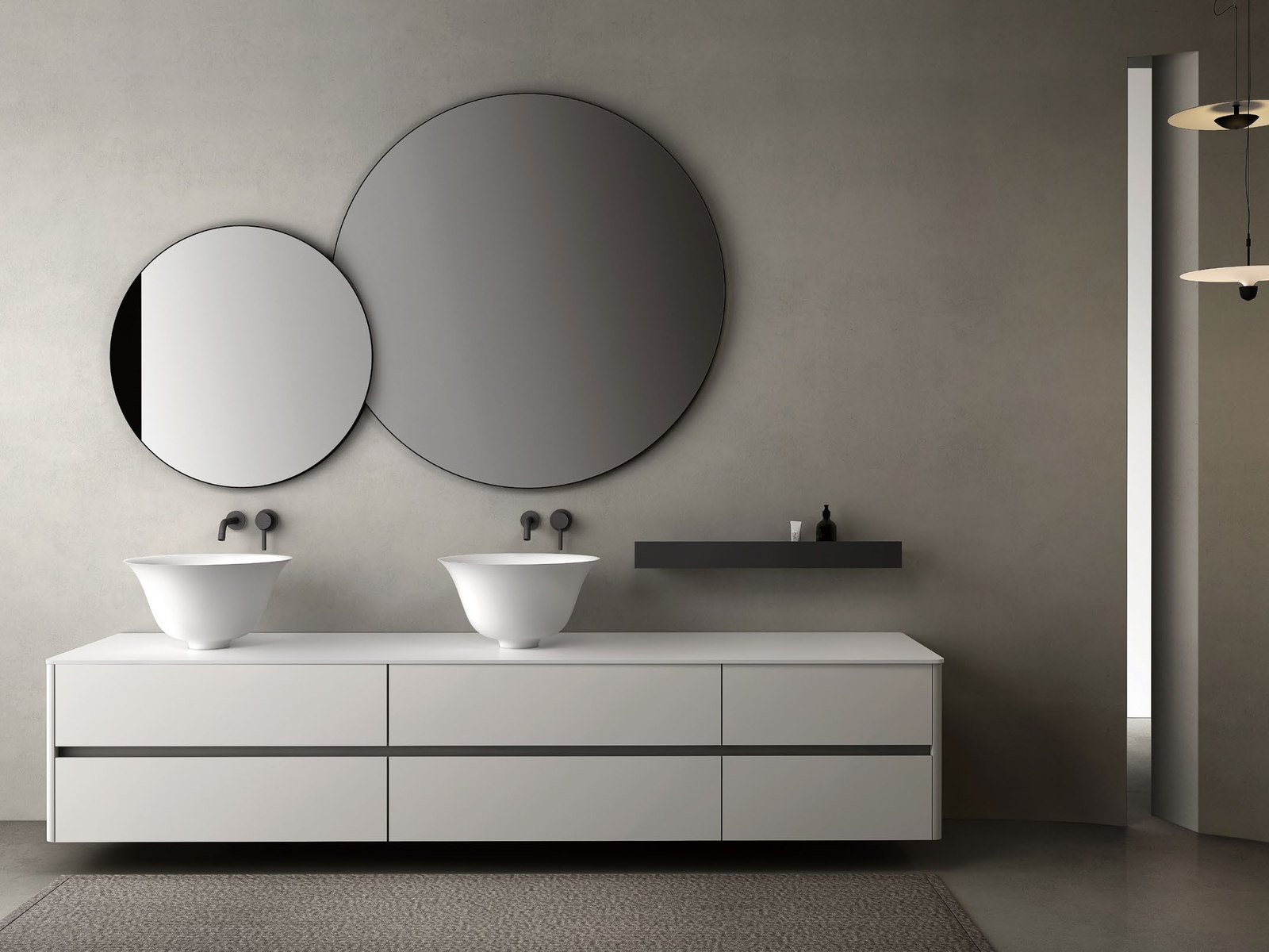 Two round lit mirrors above a double vanity with oval basins
