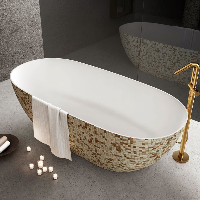 A white freestanding tub with a speckled stone base and a gold floor filler