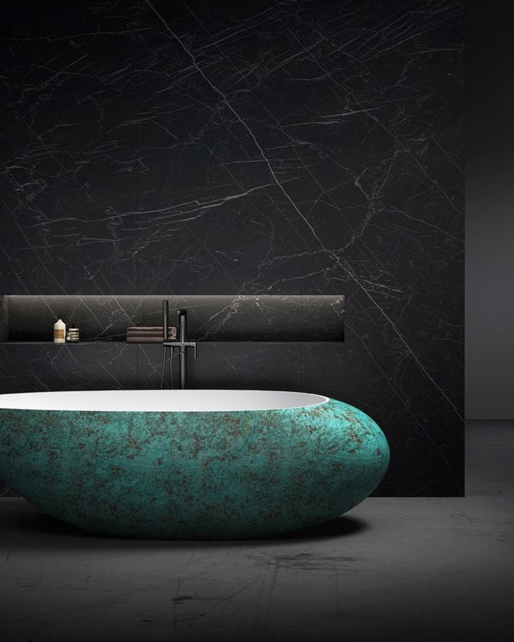 A teal-toned custom solid surface bathtub in a dark stone bathroom