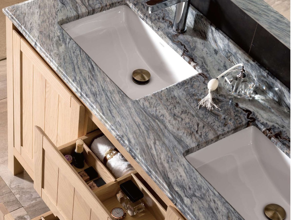 A marble vanity top with an undermount basin above a wood cabinet