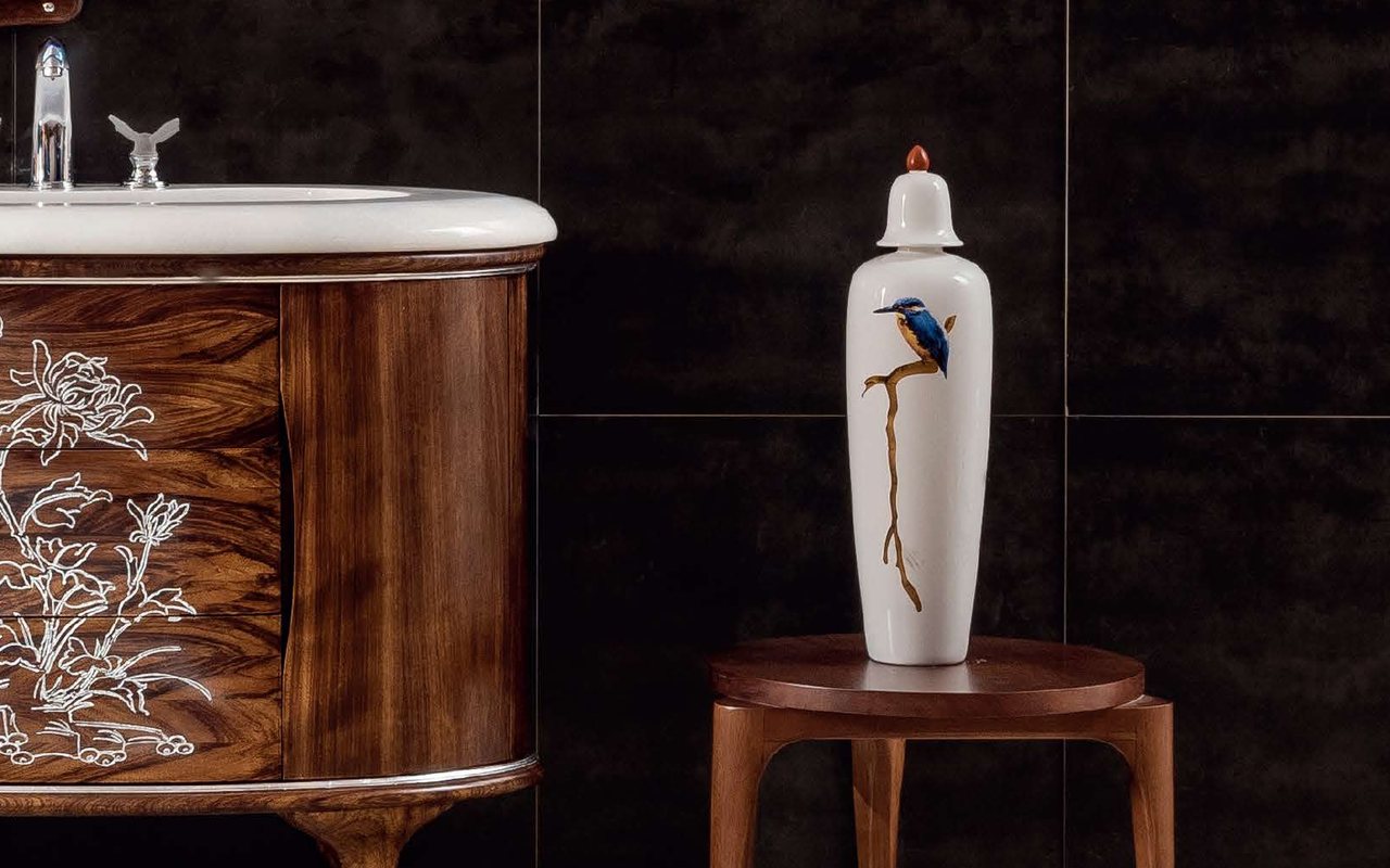 An ornate carved wood vanity beside a decorative vase