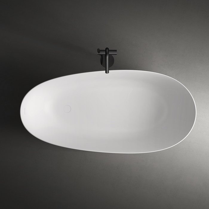 Sculpted freestanding solid surface bathtub in an arched alcove